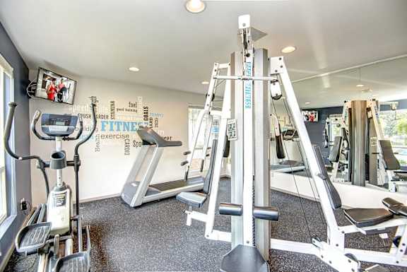 A gym with a row of treadmills and a row of exercise bikes. at The Lakes at Fife, Fife, WA