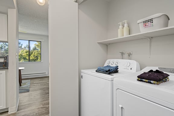 a white laundry room with a washer and dryer and a window