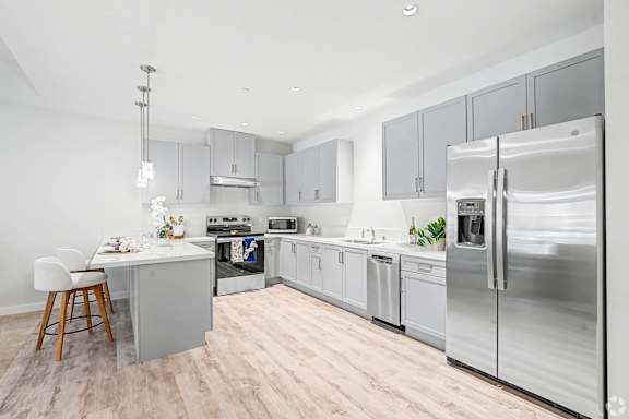 A modern kitchen with stainless steel appliances and wooden floors.