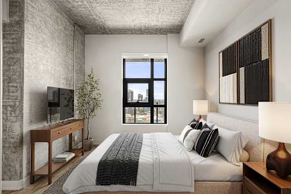 A bedroom with a large bed, a desk with a TV, and a window with a view of the city.