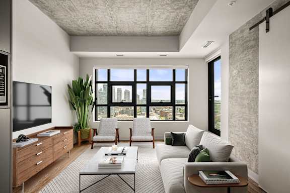 A modern living room with a grey couch, a coffee table, and a large window.