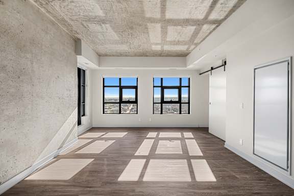 A large empty room with a window and a wooden floor.