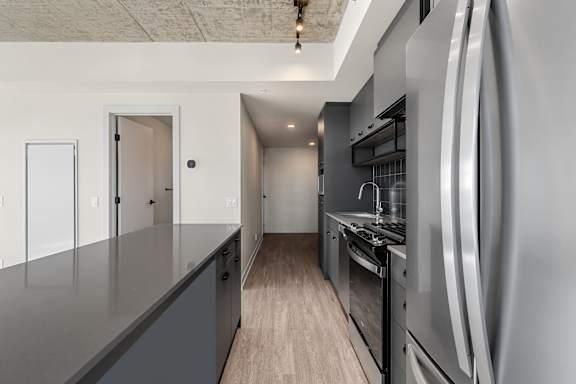 A modern kitchen with stainless steel appliances and wooden flooring.