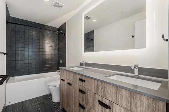 A modern bathroom with a white tub, sink, and wooden cabinets.