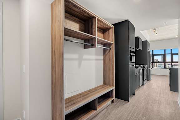 A modern kitchen with black cabinets and wooden shelves.