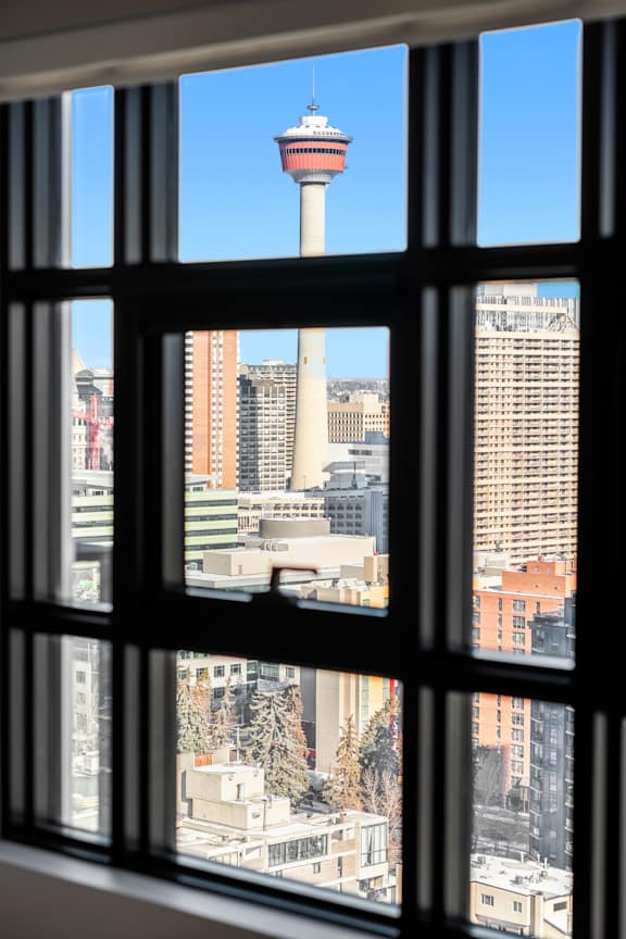 A view of a city through a window with a tall tower in the background.