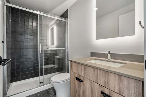 A modern bathroom with a white toilet, a sink, and a glass shower stall.