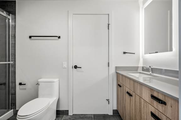 A white toilet sits next to a white door in a bathroom.