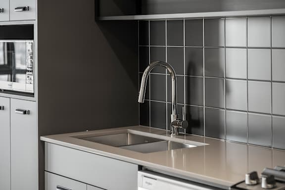 A modern kitchen with a stainless steel sink and faucet.