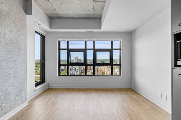 A large window with a view of a cityscape is the focal point of this empty room.