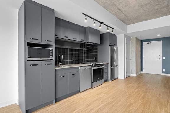 A modern kitchen with wooden floors and grey cabinets.