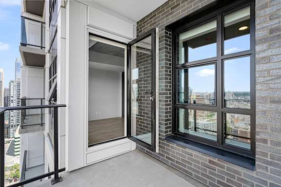 A balcony with a glass door and a black railing.