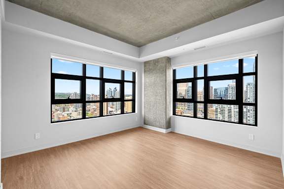 A large empty room with a view of the city through the windows.