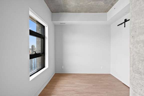 A room with a large window and wooden flooring.