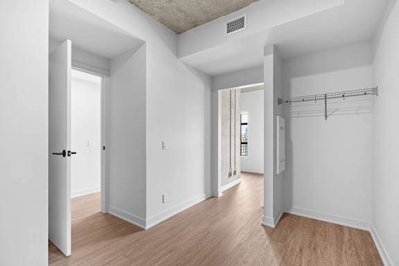 A white room with a door and a shelf.
