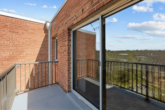 A balcony with a glass door leading to a brick building.