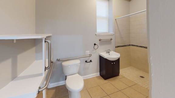 A white toilet sits in a bathroom next to a white sink.