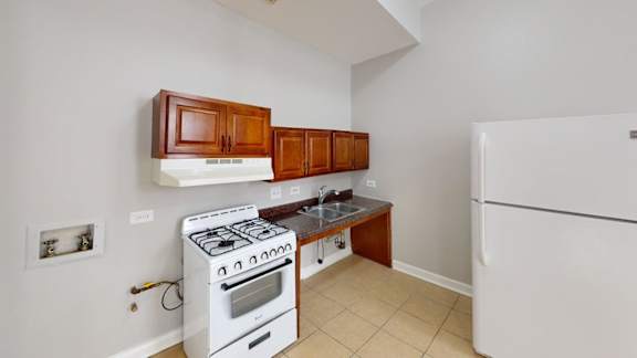 A kitchen with a white fridge, white stove and white walls.