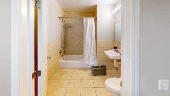 A bathroom with a white shower curtain and a white toilet.