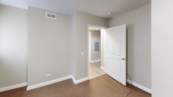 A room with a white door and carpeted floor.