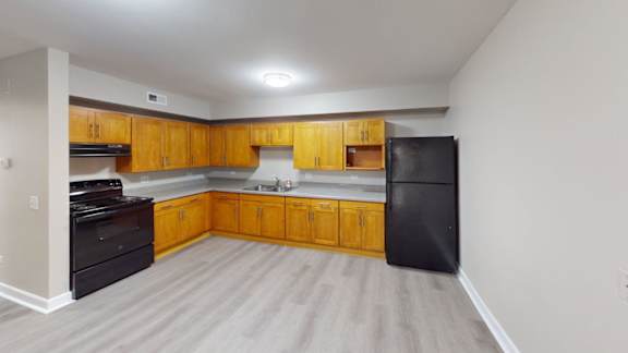 A kitchen with wooden cabinets and a black fridge.