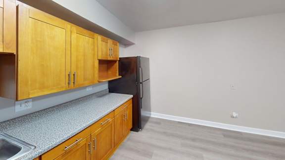 A kitchen with wooden cabinets and a black refrigerator.