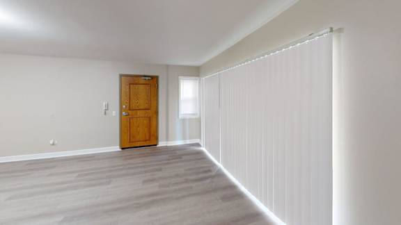 A room with a wooden door and a window with blinds.