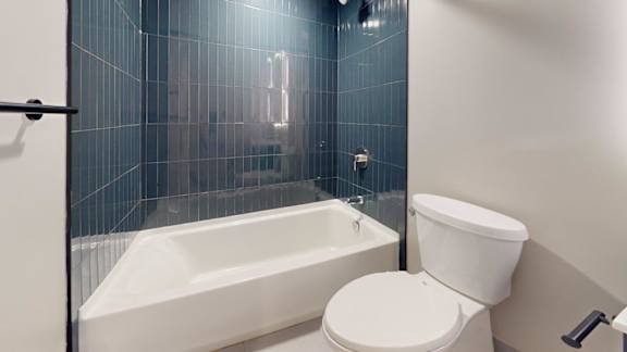 A white toilet sits next to a bathtub in a bathroom.