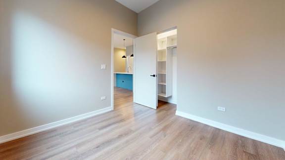 A room with a wooden floor and a doorway leading to another room.