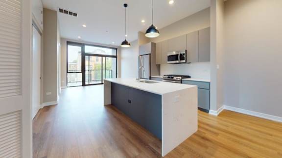A modern kitchen with a white island and dark wood floors.
