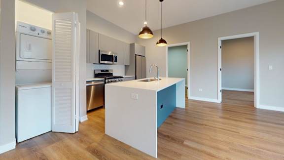 A kitchen with a white fridge and a white island with a blue drawer.