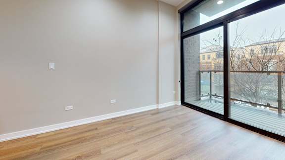 A room with wooden flooring and a sliding glass door.