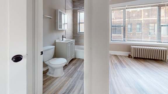 A bathroom with a toilet, sink, and window.