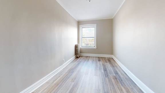 A room with a window and wooden flooring.