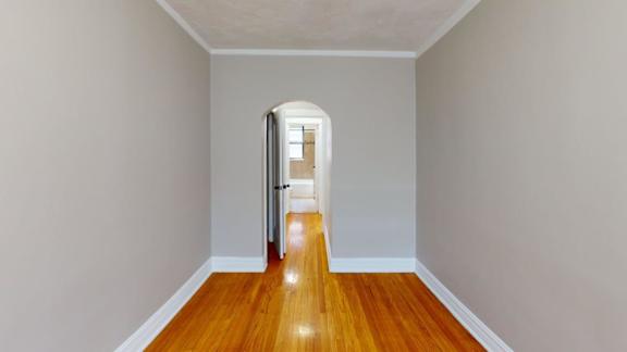 A hallway with a wooden floor and a white door.