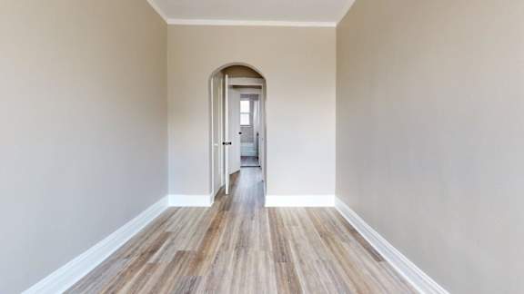 A hallway with a wooden floor and a doorway at the end.