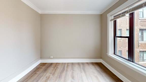 Empty room with wooden flooring and a window.