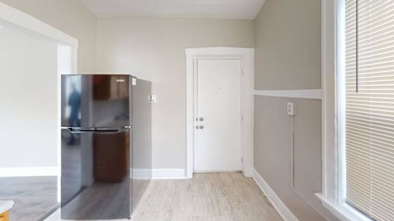 A black fridge in a room with a white door.