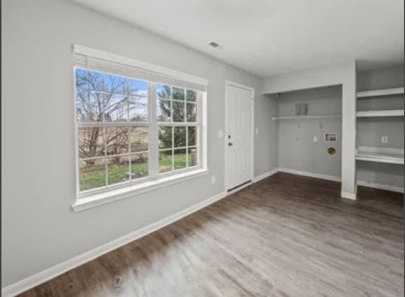 a living room with a large window and wooden floors
