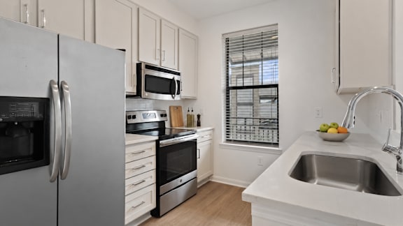 A kitchen with a stainless steel refrigerator, microwave, oven, and sink.