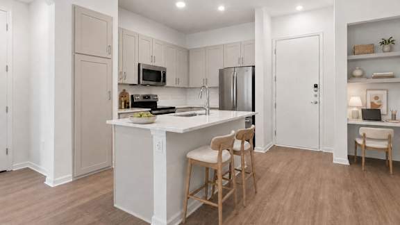 A kitchen with a white island and wooden chairs.