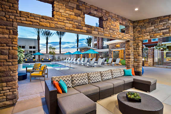 A patio with a pool and lounge chairs.