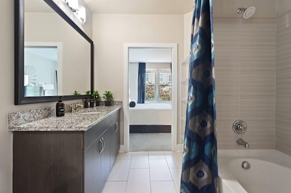 A bathroom with a large mirror, a sink, and a bathtub.