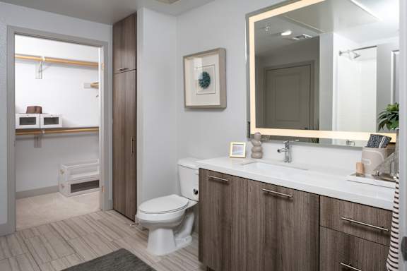 A bathroom with a toilet, sink, and mirror.