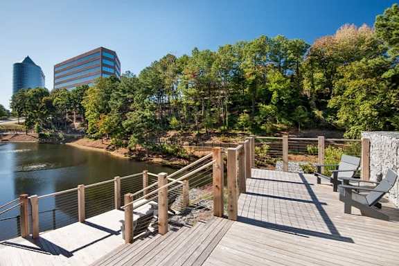 A wooden deck overlooks a body of water with trees in the background.