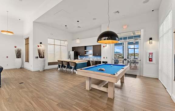 A room with a pool table and a bar area.