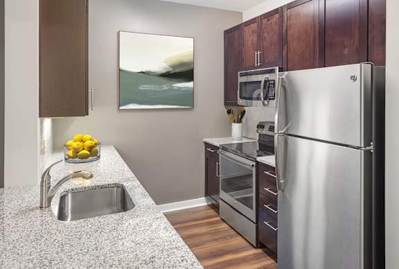 A modern kitchen with a stainless steel refrigerator and a granite countertop.