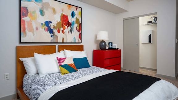A bedroom with a large bed and a colorful painting above it.