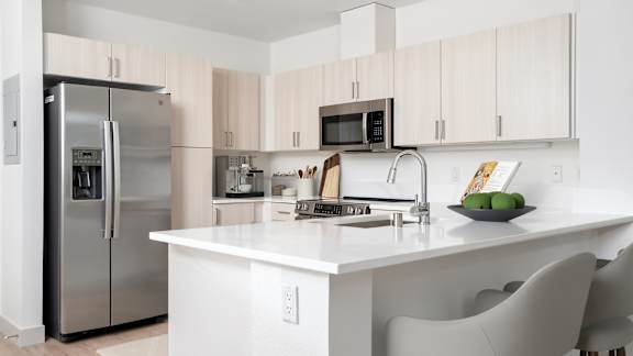 A modern kitchen with a refrigerator, microwave, and sink.