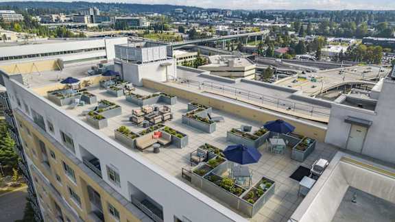 A rooftop patio with tables and chairs overlooks a cityscape.